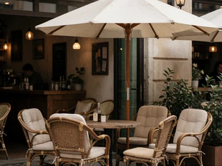 A shaded patio seating area at a cafe with cushioned chairs, representing a cool accessible date venue for someone with MS