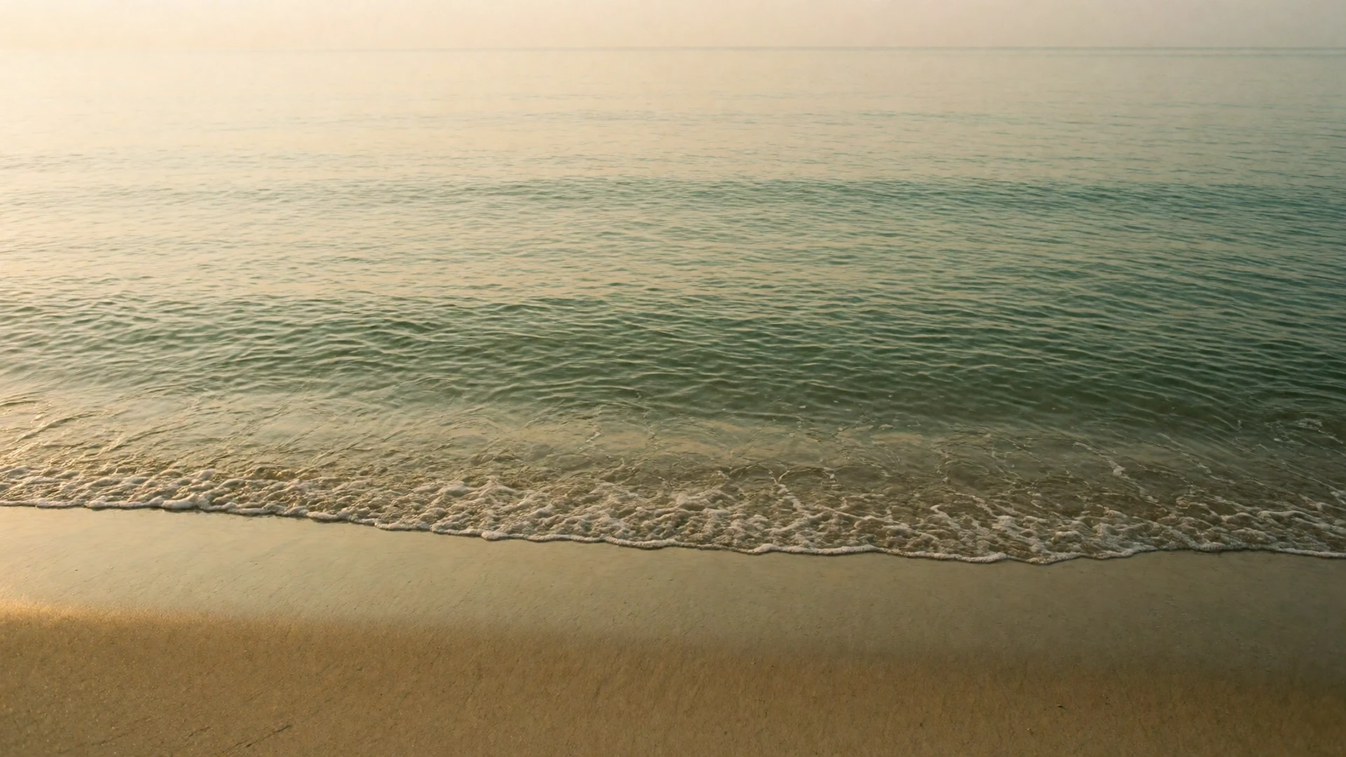 A calm beach at dawn with soft golden light over gentle waves, representing a peaceful grounding scene for overcoming dating anxiety