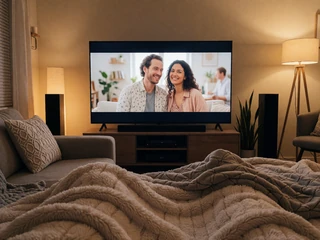 A cozy home movie setup with soft lighting and blankets, representing a predictable low-stimulation at-home date